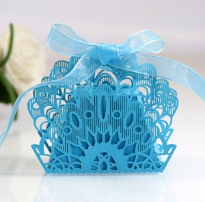 Close-up of laser-cut wedding favor box in sky blue with elegant organza ribbon bow