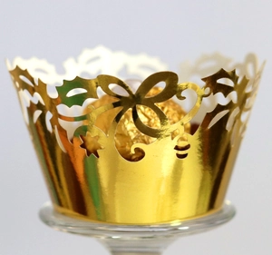 Macro detail of laser-cut gold cupcake wrapper with hollow vine and bow patterns