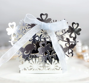 Close-up of laser-cut hollow candy box with bird and heart patterns and blue silk ribbon