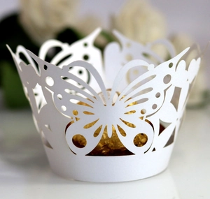 Detail of laser cut butterfly cupcake wrapper in white paper for wedding dessert table