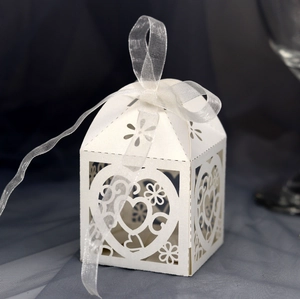 Macro detail of white laser-cut hollow heart pattern on wedding favor gift box with ribbon