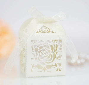 Macro shot of laser-cut rose patterns on a cream wedding candy box with ribbon