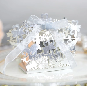 Macro shot of silver laser-cut wedding favor box with snowflakes and blue ribbon