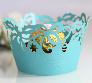 Macro view of cyan laser-cut cupcake wrapper with holly leaf and star pattern