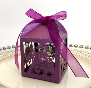 Detail of purple laser-cut elephant candy box with sheer organza ribbon on a plate
