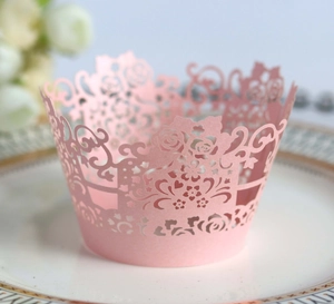 Detailed laser-cut pink rose flower cupcake wrapper on white porcelain plate