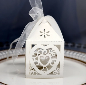 Detailed laser-cut heart pattern on white house-shaped wedding candy box with ribbon