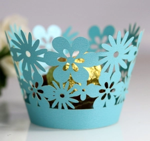 Macro detail of laser-cut light blue daisy cupcake wrapper with floral hollow patterns