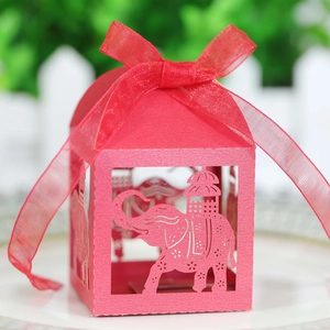 Macro shot of red laser-cut elephant candy box with elegant ribbon for party favors