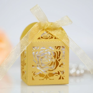Detail of laser-cut rose pattern on gold pearlescent paper gift box with ribbon