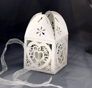 Close-up of laser-cut white heart wedding candy box with delicate organza ribbon