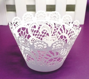 Detailed close-up of intricate white lace laser-cut cupcake wrapper for party decor