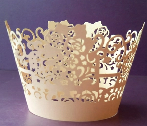 Intricate laser-cut cream cupcake wrapper with elegant floral hollow-out pattern