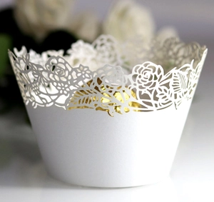 Macro detail of laser-cut white rose lace cupcake wrapper with intricate floral pattern