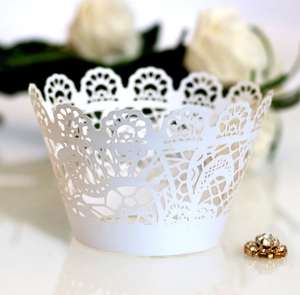 Close-up of white laser-cut lace cupcake wrappers with elegant floral crown pattern