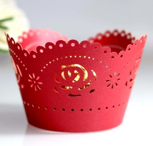 Detail view of red laser-cut cupcake wrappers featuring elegant rose hollow patterns