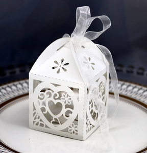 Detailed laser-cut heart pattern on a white favor box with elegant ribbon bow