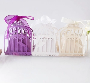 Detailed laser-cut birdcage candy boxes in purple, white, and beige with elegant silk ribbons