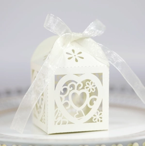 Macro detail of laser-cut heart pattern on pearlescent wedding candy gift box with ribbon