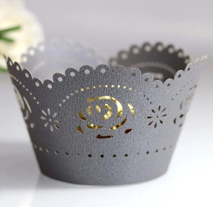 Macro detail of laser-cut rose patterns on elegant grey and gold cupcake wrappers