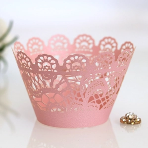 Macro detail of laser-cut pink lace cupcake wrapper with intricate floral hollow patterns