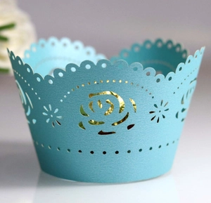 Macro detail of light blue laser-cut cupcake wrapper with rose pattern and pearlescent finish