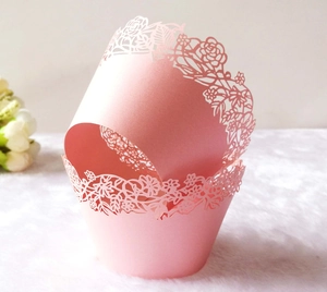 Close-up of pink laser-cut cupcake wrappers with elegant rose patterns for weddings