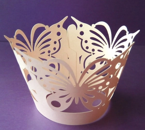 Close-up of laser-cut cupcake wrapper featuring elegant hollow butterfly patterns