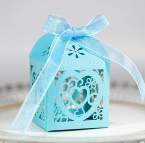 Macro detail of laser-cut heart patterns on a light blue wedding favor gift box with ribbon