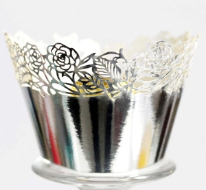 Macro detail of silver laser-cut cupcake wrappers featuring hollow rose flower patterns
