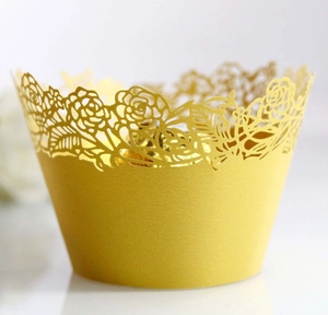 Close-up of golden cupcake wrappers with laser-cut hollow rose pattern and elegant finish