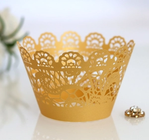 Macro shot of laser-cut gold lace cupcake wrappers with elegant hollowed-out patterns