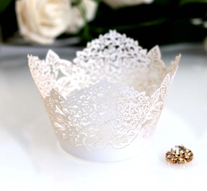 Detail of laser-cut white cupcake wrapper featuring elegant floral lace patterns for parties