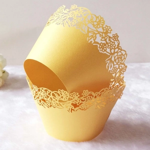 Detail of laser-cut gold floral lace pattern on paper cupcake wrappers for weddings