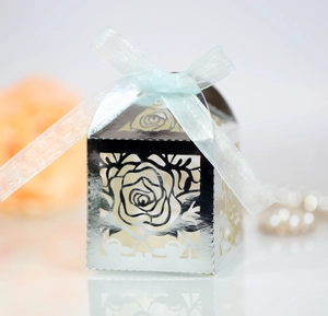 Detail of silver laser-cut wedding favor box with rose patterns and light blue ribbon
