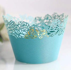 Close-up of laser-cut teal cupcake wrapper with elegant rose patterns for weddings