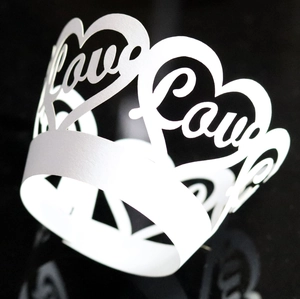 Macro detail of laser-cut wedding cupcake wrapper with white lace heart and Love pattern