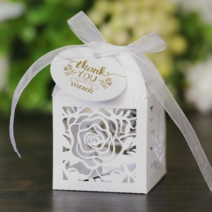 Macro shot of white laser-cut rose gift box with silk ribbon and gold Thank You tag