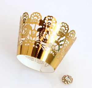 Macro shot of gold laser-cut lace cupcake wrapper with crown pattern and rhinestone