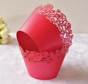 Macro shot of red laser-cut cupcake wrappers with hollow lace flower pattern for weddings