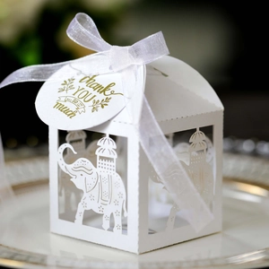 Detail of white laser-cut elephant favor box with elegant silk ribbon and thank you tag
