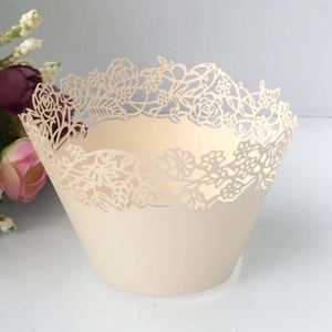 Detail of laser-cut rose and daisy hollow patterns on beige cupcake paper wrappers