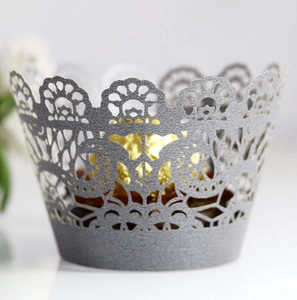 Macro detail of laser-cut silver lace cupcake wrapper with intricate floral hollow design