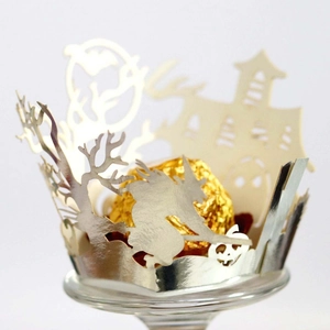 Macro shot of laser-cut Halloween cupcake wrapper with silver castle and witch motifs