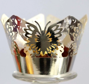 Macro detail of laser-cut gold cupcake wrappers featuring hollow butterfly and floral designs