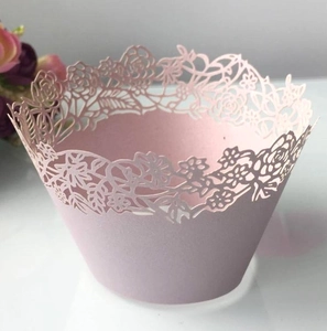 Intricate laser-cut cupcake wrapper with pink floral lace patterns for wedding party decor