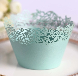 Detailed laser-cut mint green cupcake wrapper with intricate floral and leaf patterns