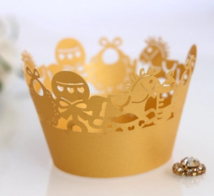 Detail of gold laser-cut cupcake wrappers with intricate carousel and heart patterns