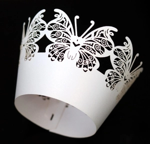 Macro shot of laser-cut white butterfly lace paper cupcake wrappers with pearlescent finish