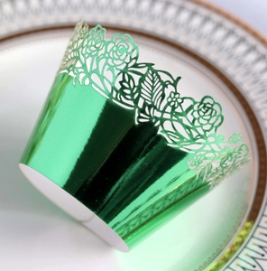 Macro shot of metallic green laser-cut cupcake wrappers with rose floral patterns